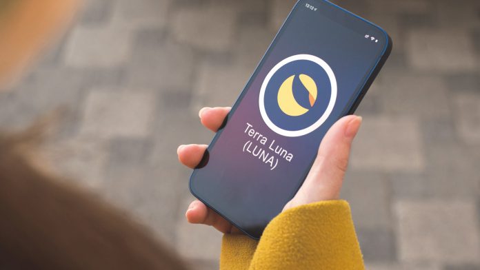 Terra Luna cryptocurrency symbol, logo. Business and financial concept. Hand with smartphone, screen with crypto icon closeup